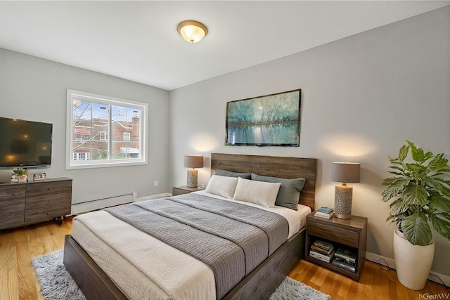 bedroom featuring baseboards, baseboard heating, and wood finished floors