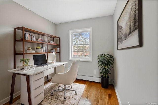 office space with a baseboard heating unit, wood finished floors, and baseboards