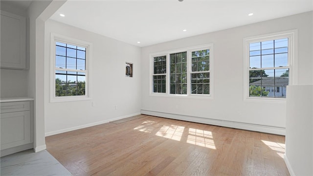 spare room featuring recessed lighting, baseboards, a wealth of natural light, and a baseboard radiator