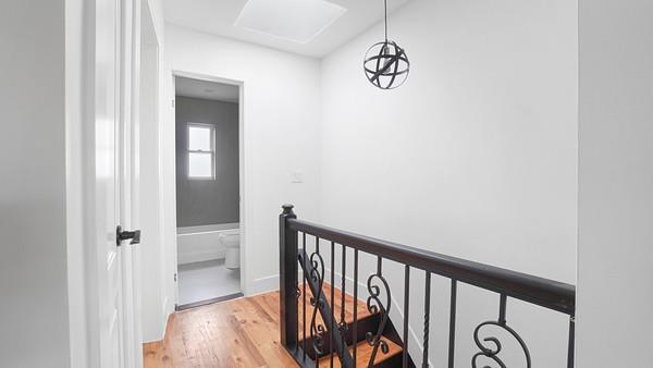 corridor featuring an upstairs landing and light wood finished floors