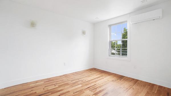 spare room featuring light wood finished floors, baseboards, and a wall unit AC