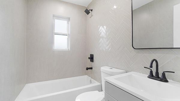 bathroom with vanity, tub / shower combination, decorative backsplash, tile walls, and toilet