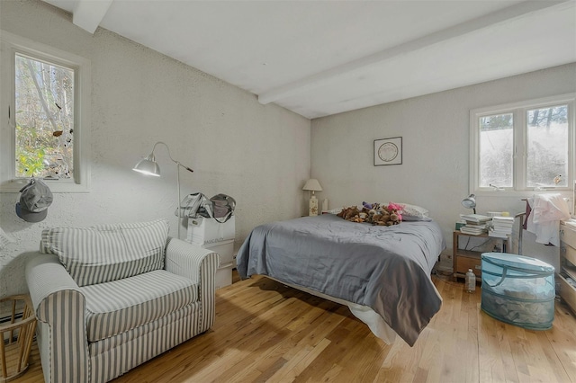 bedroom featuring beam ceiling and wood finished floors