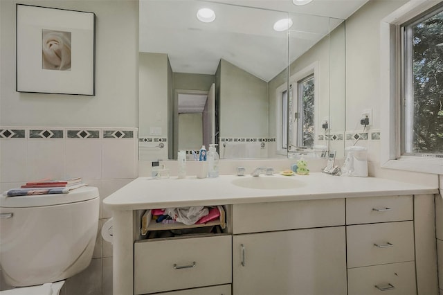 bathroom featuring tile walls, plenty of natural light, toilet, and vanity