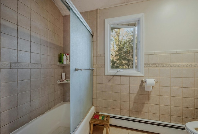 bathroom with baseboard heating, combined bath / shower with glass door, toilet, and tile walls