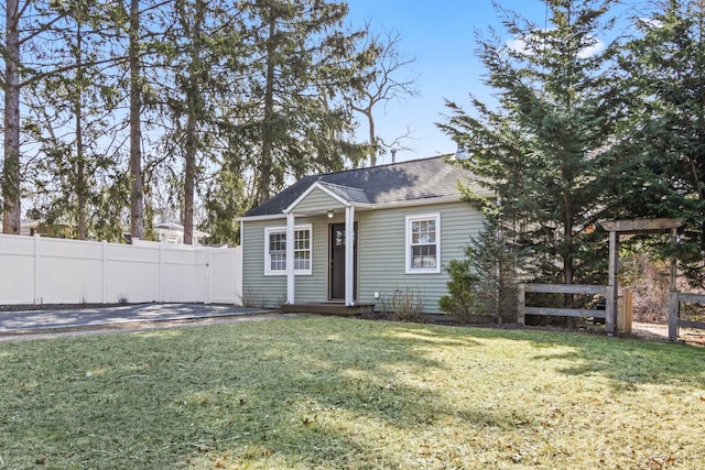 view of front of house featuring a front yard, fence, and roof with shingles