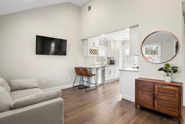 living room featuring high vaulted ceiling, dark wood-style floors, visible vents, and baseboards