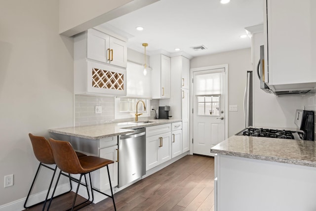 kitchen with backsplash, range with gas cooktop, dishwasher, wood finished floors, and a sink