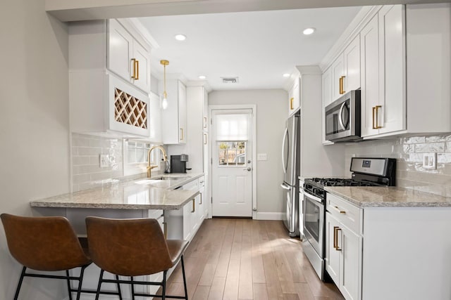 kitchen with white cabinetry, wood finished floors, appliances with stainless steel finishes, and a sink