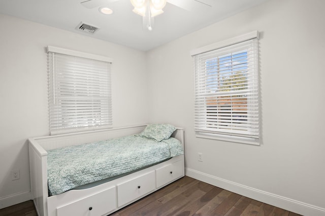 bedroom with dark wood-style floors, visible vents, ceiling fan, and baseboards