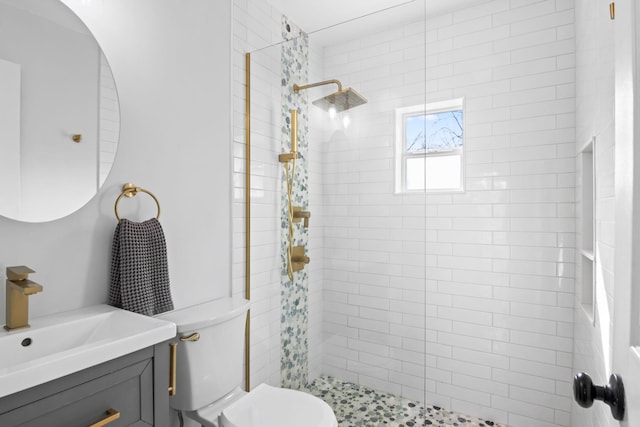 bathroom with toilet, vanity, and a tile shower