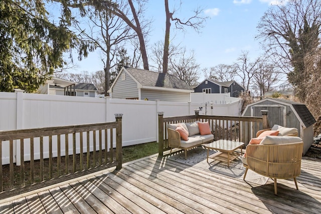 wooden deck featuring outdoor lounge area, an outdoor structure, a storage unit, and a fenced backyard