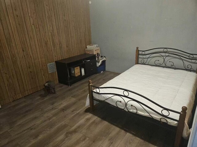 bedroom featuring wooden walls and wood finished floors