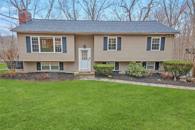 raised ranch featuring a front lawn and a chimney