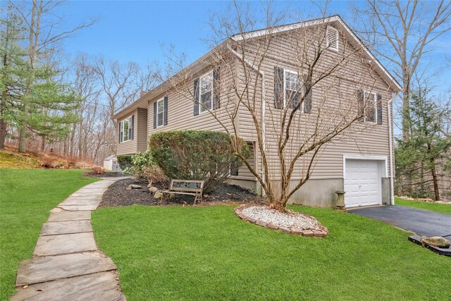 view of side of property with a lawn, driveway, and a garage