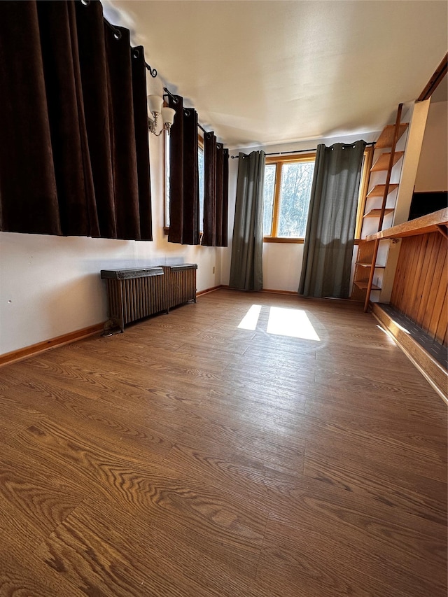 empty room with radiator heating unit, wood finished floors, and baseboards