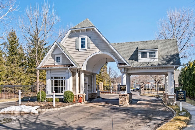 exterior space with driveway, a shingled roof, and fence