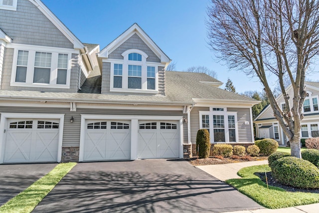 view of front of property with aphalt driveway, an attached garage, stone siding, and a shingled roof