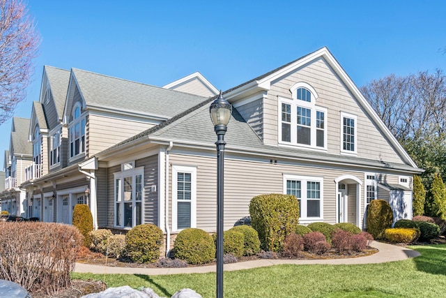 view of front of house with a garage, a front lawn, and a shingled roof