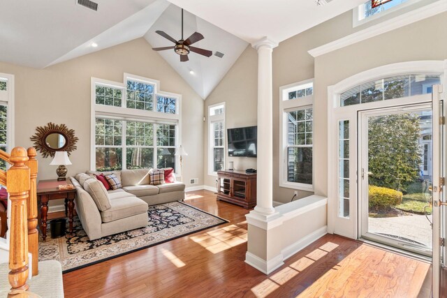 living room featuring decorative columns, wood finished floors, visible vents, and high vaulted ceiling