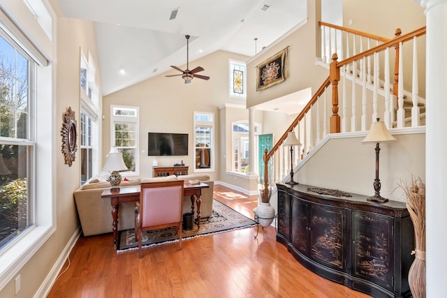 living area with visible vents, a healthy amount of sunlight, high vaulted ceiling, and hardwood / wood-style flooring