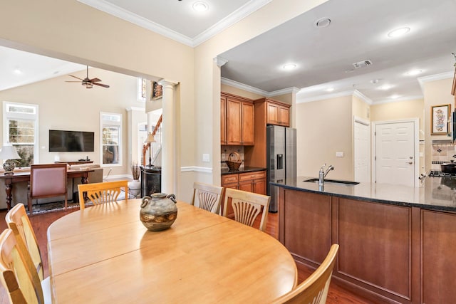 dining space featuring crown molding, decorative columns, ceiling fan, and wood finished floors