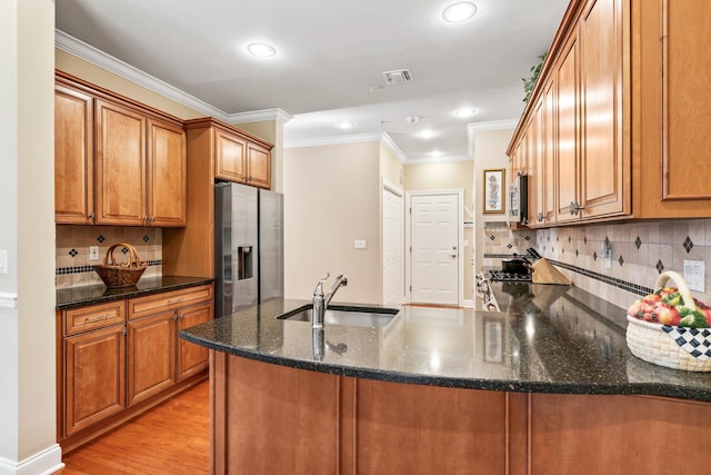 kitchen featuring dark stone countertops, brown cabinets, appliances with stainless steel finishes, and a sink