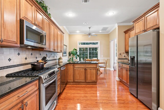 kitchen with a sink, stainless steel appliances, ornamental molding, and brown cabinetry