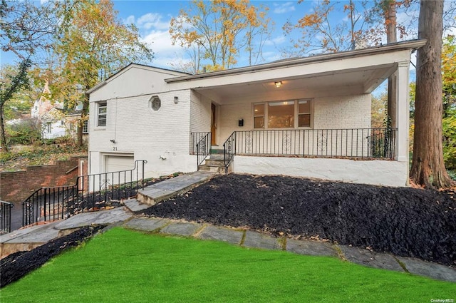 view of front of home featuring brick siding, a porch, a front yard, and a garage