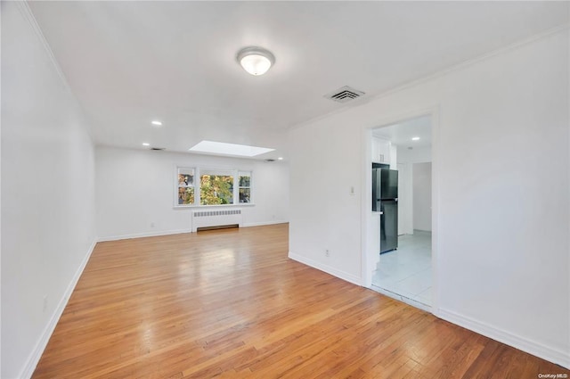 21 Ravine Rd, Great Neck, NY 11023 - unfurnished living room featuring visible vents, radiator heating unit, light wood-style floors, a skylight, and baseboards