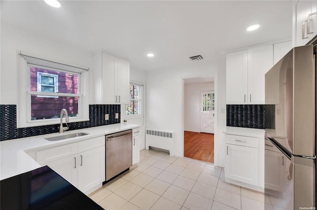 21 Ravine Rd, Great Neck, NY 11023 - kitchen with visible vents, radiator, white cabinets, stainless steel appliances, and a sink