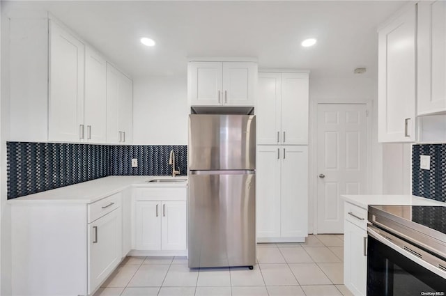 21 Ravine Rd, Great Neck, NY 11023 - kitchen with light tile patterned floors, a sink, stainless steel appliances, white cabinets, and backsplash