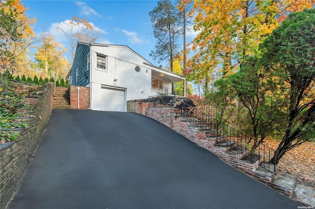 21 Ravine Rd, Great Neck, NY 11023 - view of side of home with brick siding, fence, aphalt driveway, stairway, and an attached garage