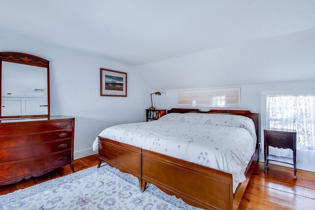 bedroom featuring vaulted ceiling, baseboards, and hardwood / wood-style flooring