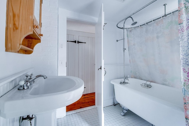 full bathroom with tile patterned flooring, a shower with shower curtain, a freestanding bath, and a sink