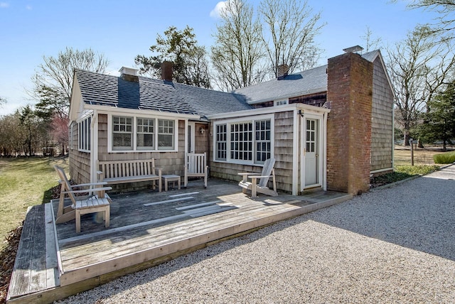 rear view of property with a wooden deck and roof with shingles