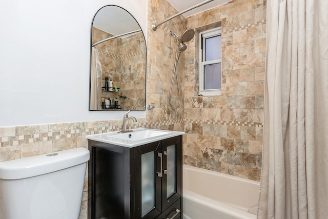 bathroom featuring toilet, vanity, shower / bath combo with shower curtain, and tile walls