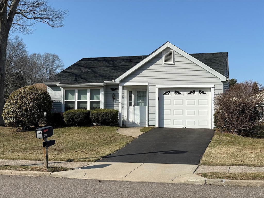 single story home featuring an attached garage, a front yard, driveway, and roof with shingles