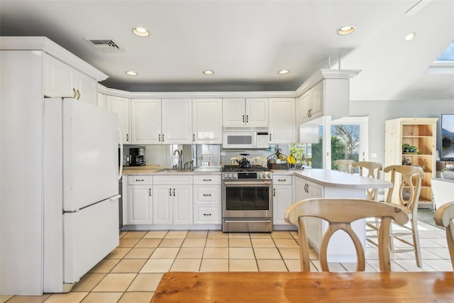 kitchen featuring visible vents, light tile patterned flooring, white appliances, white cabinetry, and a sink