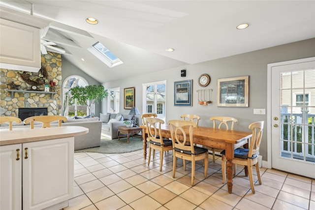 dining area featuring recessed lighting, vaulted ceiling with skylight, light tile patterned flooring, and a fireplace