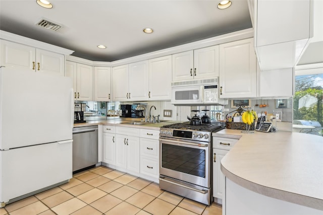 kitchen featuring visible vents, a sink, appliances with stainless steel finishes, white cabinets, and light countertops