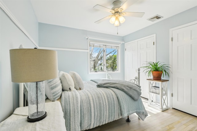 bedroom with a closet, visible vents, ceiling fan, and wood finished floors