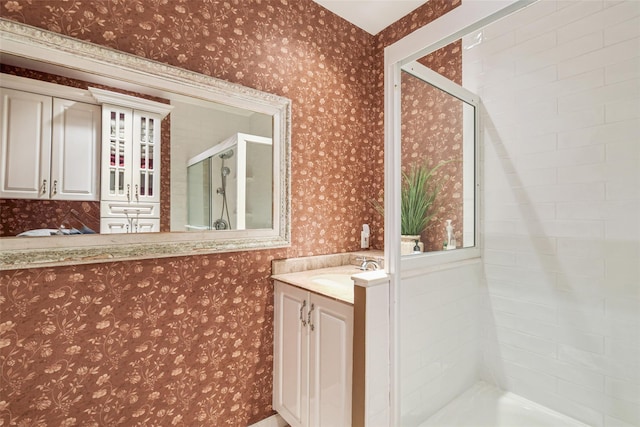 bathroom with vanity, a shower stall, and wallpapered walls