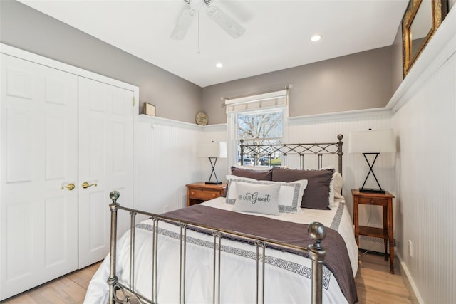 bedroom featuring light wood-type flooring, baseboard heating, and wainscoting