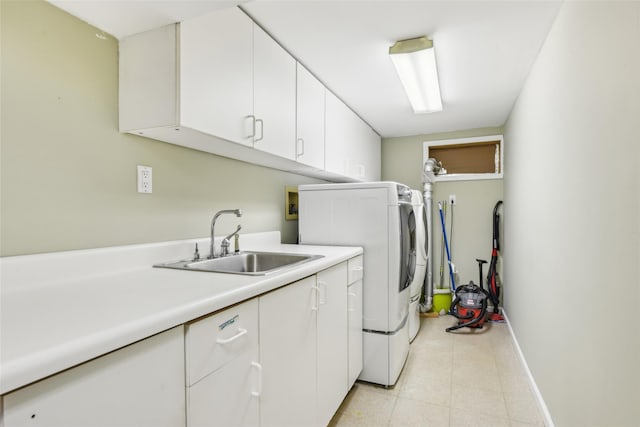 laundry area with a sink, baseboards, cabinet space, and washer / dryer