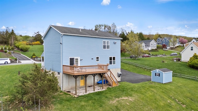 back of property featuring a wooden deck, fence, stairs, a storage unit, and a yard
