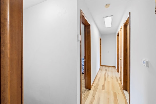 hallway featuring baseboards and light wood-style floors