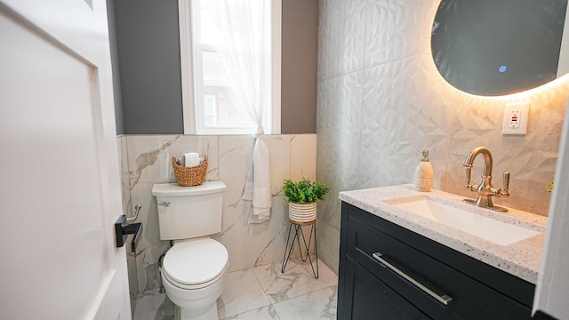 bathroom featuring marble finish floor, vanity, tile walls, and toilet