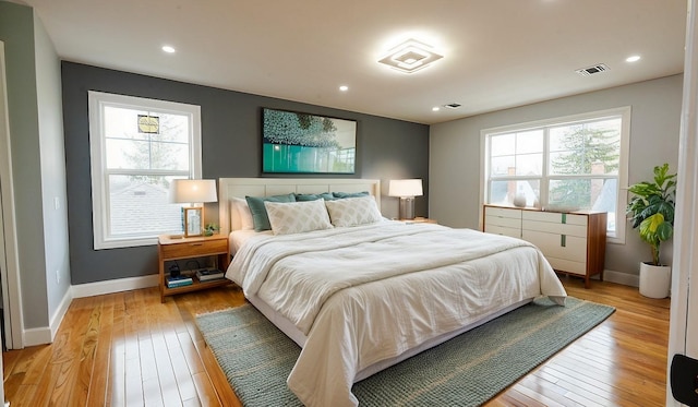 bedroom with visible vents, multiple windows, baseboards, and light wood-style floors