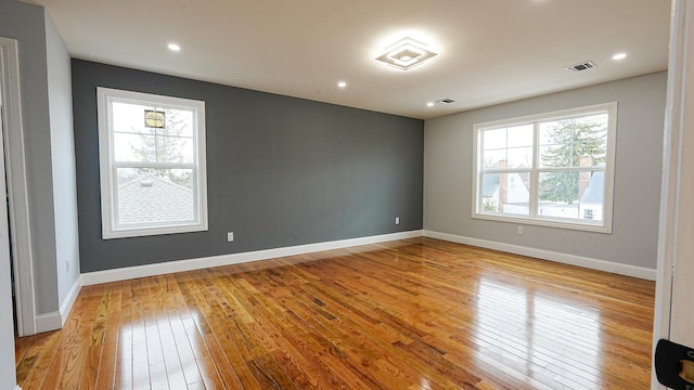 spare room featuring light wood-style flooring, recessed lighting, baseboards, and visible vents